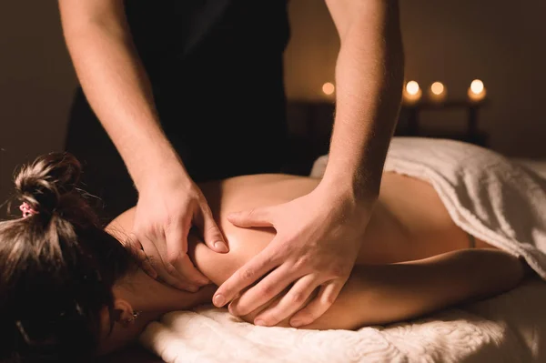 Acercamiento Trabajador manual masculino haciendo masaje de spa a una joven en una habitación oscura —  Fotos de Stock