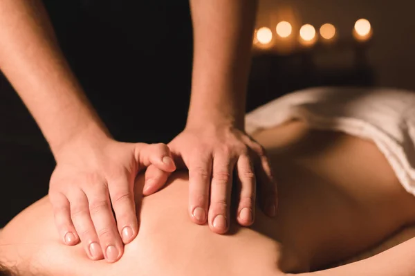Acercamiento Trabajador manual masculino haciendo masaje de spa a una joven en una habitación oscura —  Fotos de Stock
