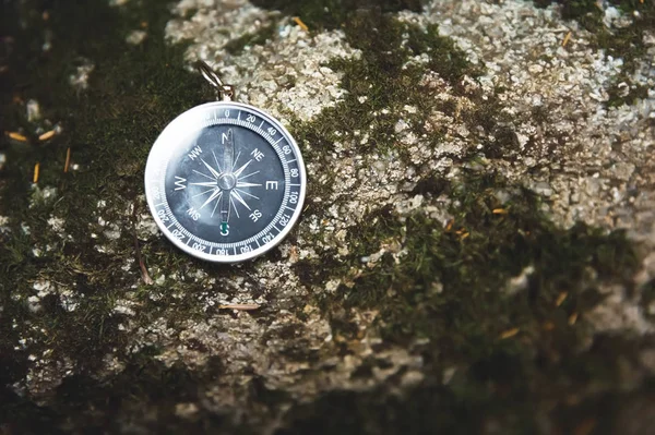 Магнитный компас с черным циферблатом на диком камне, покрытом зеленым мхом. Концепция поиска пути и решения — стоковое фото
