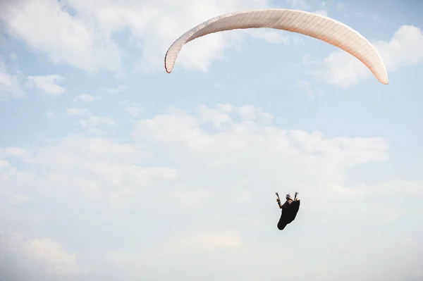 Profi-Gleitschirmflieger im Kokon-Anzug fliegt hoch über dem Boden gegen den Himmel — Stockfoto