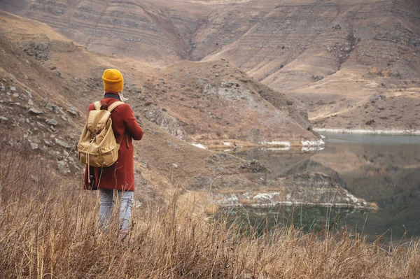 A portrait from the back of a girl traveler on the background of a lake in the mountains in autumn or early spring. Travel concept — Stock Photo, Image