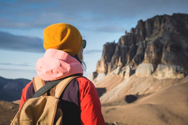 Close-up Ritratto dal retro di una ragazza viaggiatrice in giacca con cappuccio e zaino sullo sfondo di un paesaggio epico con rocce — Foto Stock