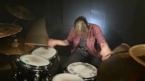 Bateristas de cabelos compridos tocam bateria em uma sala escura em um fundo preto. Músico de rock. Plano estático. Ângulo largo — Vídeo de Stock