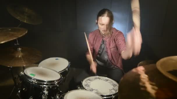 Dlouhé vlasy-bubeníci hrají bicí souprava v temné místnosti na černém pozadí. Rockový hudebník. Statický plán. Široký úhel — Stock video