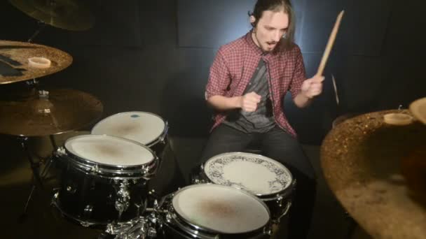 Long-haired drummers play drum kit in a dark room on a black background. Rock musician. Static plan. Wide angle — Stock Video