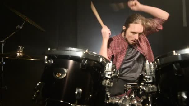 Long-haired drummers play drum kit in a dark room on a black background. Rock musician. Static plan. Wide angle — Stock Video