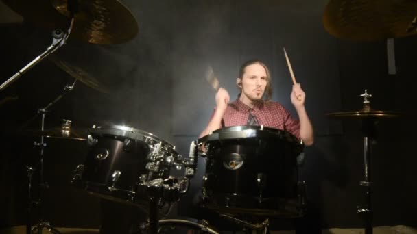 Bateristas de cabelos compridos tocam bateria em uma sala escura em um fundo preto. Músico de rock. Plano estático. Ângulo largo — Vídeo de Stock