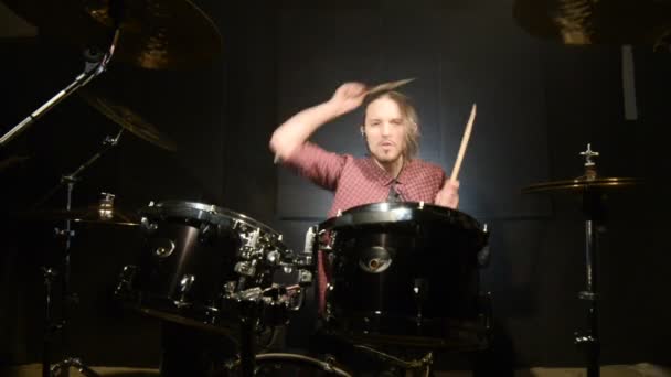 Long-haired drummers play drum kit in a dark room on a black background. Rock musician. Static plan. Wide angle — Stock Video