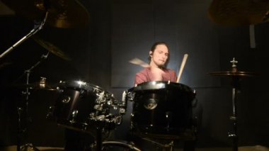 Uzun saçlı davulcular davul kiti karanlık bir odada bir siyah arka plan üzerinde oynamak. Rock müzisyeni. Statik plan. Geniş açı