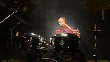 Beat şarkı intro üzerinde müzik davul sopa el ile ayarla davul oturan uzun saçlı bir davulcu sways. davul çalma zevk. Statik plan. Geniş açı