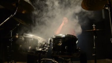Uzun saçlı bir davulcu bir davul kiti oturan bir vape ile asılı. Vape kültür müzik. Statik plan
