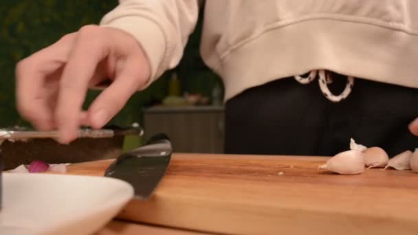 Close-up van handen van een meisje op de binnenlandse keuken op een houten snijplank verplettert eerlijk tanden om ze schoon te maken. Home koken — Stockvideo