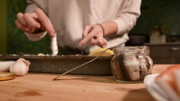 家庭の台所で女の子の手のクローズ アップは、皿が付いている皿にガラスの瓶からスプラットを産みます。健全な家庭料理 — ストック動画