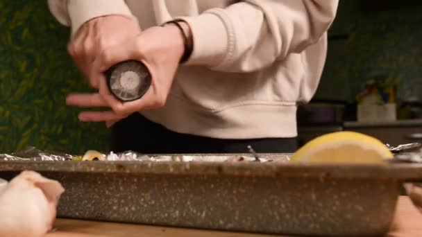 Крупным планом руки девушки на домашней кухне солят или перчат блюдо в продвине ручной мельницы. Здоровое домашнее питание — стоковое видео