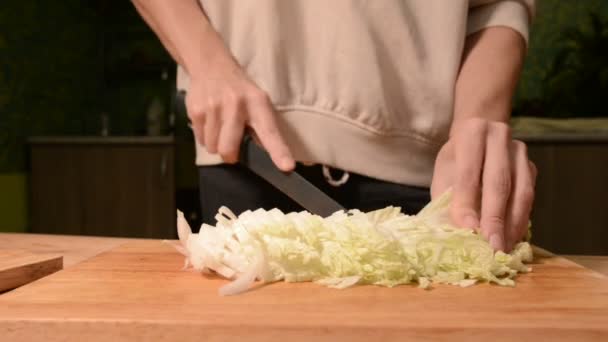 Крупным планом руки девушки на домашней кухне на деревянных ножах режущей доски Пикинский капуста для салата. Домашняя кухня — стоковое видео