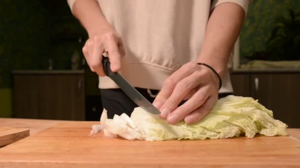 El primer plano de las manos de una chica en la cocina del hogar en una tabla de cortar de madera cuchillos Pikinsky repollo para ensalada. Cocina casera — Vídeo de stock