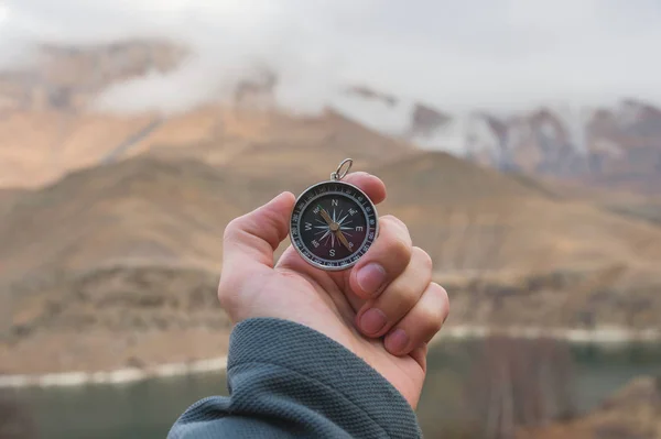 Een mannelijke wandelaar is op zoek naar een richting met een magnetisch kompas in de bergen in de herfst. Oogpunt geschoten. Mans van de hand met een horloge armband houdt een kompas — Stockfoto