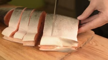 Eller Close-up büyük somon ev yemekleri, ahşap bir masa üzerinde bir bıçak ile kesme