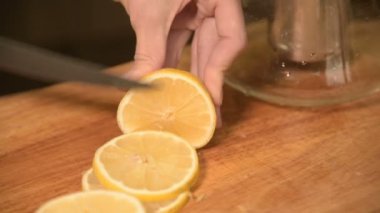 Closeup ev mutfak ahşap kesme tahtası üzerinde bir kıza el. Sarı limon gezginci üzerinde keser. Ev yemekleri