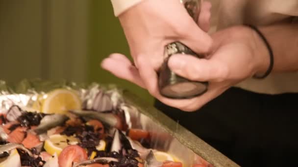 Close-up of hands of a girl at the home kitchen is salting or peppering a dish in a prodvin of a manual mill. Healthy home cooking — Stock Video