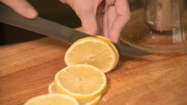 木製のまな板に家庭の台所で女の子の手のクローズ アップ。ベビーカーに黄色いレモンをカットします。ホーム クッキング — ストック動画