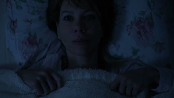 Close-up of a girl at night lying in bed and can not sleep looking at the ceiling. View from above — Stock Video