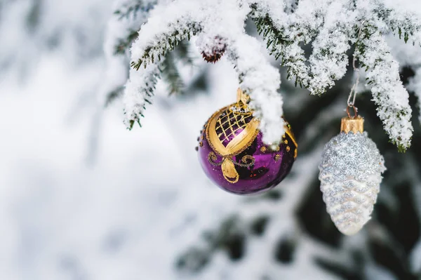 Close-up Christmas toys on a snow-covered live tree in the winter forest — Stock Photo, Image