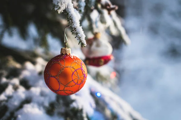 Close-up de um brinquedo de Natal em uma árvore animada coberta de neve na floresta de inverno no fundo das luzes — Fotografia de Stock