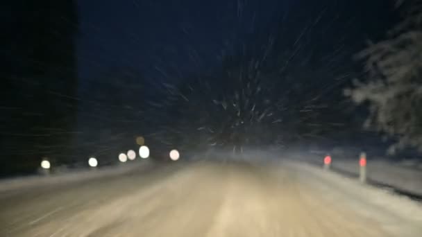 Bir kış ormanı karlı bir yol boyunca geceleri araba. Ön camın uçan kar pul odaklanmak — Stok video