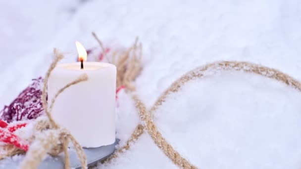 Un primer plano de un oso de peluche con velas de Navidad en un acogedor cuadros a cuadros al aire libre junto a una caja de regalo roja salpicada de nieve. Ánimo festivo de Navidad — Vídeos de Stock
