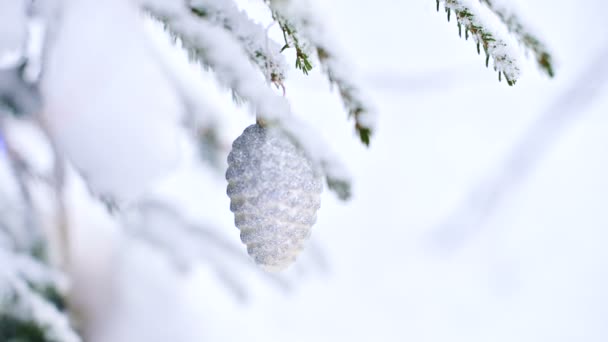 Primer plano de un juguete de Navidad en un árbol animado cubierto de nieve en el bosque de invierno en el fondo de luces. Pequeño DOF — Vídeo de stock