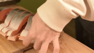 Eller Close-up büyük somon ev yemekleri, ahşap bir masa üzerinde bir bıçak ile kesme