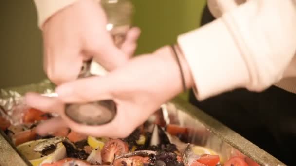 Die Nahaufnahme der Hände eines Mädchens in der heimischen Küche ist das Salzen oder Pfeffern einer Speise in einem Produkt einer manuellen Mühle. gesunde Hausmannskost — Stockvideo