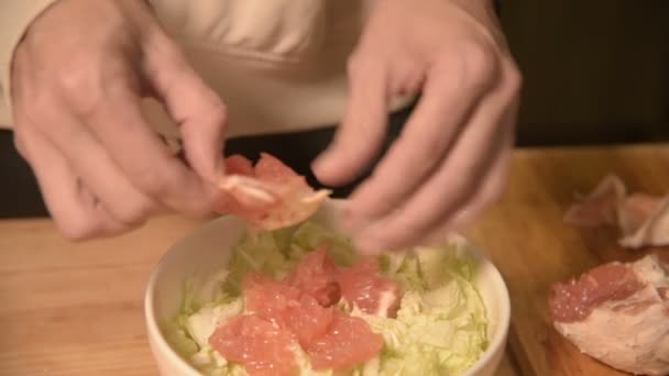 Close-up van handen een meisje op de binnenlandse keuken reinigt en hakt grapefruit voor een vegetarische salade. Gezond thuis koken — Stockvideo