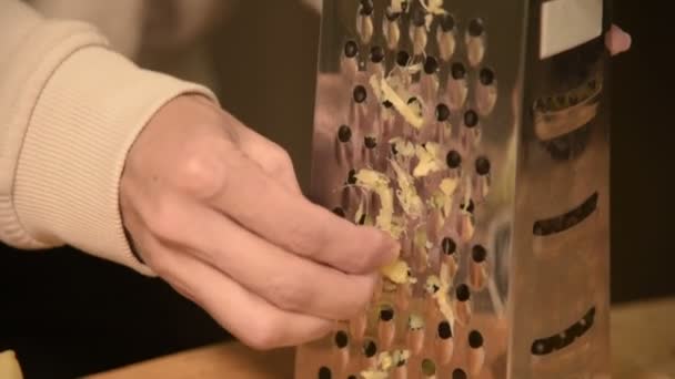 Γκρο πλαν γυναικείο χέρι τρίβει καθαρίζονται ρίζα τζίντζερ σε έναν μεταλλικό τρίφτη. Υγιεινά φυσικά τρόφιμα — Αρχείο Βίντεο