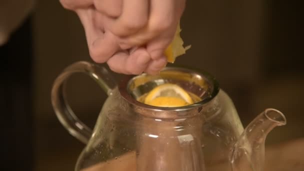 Close-up de mãos femininas estão cortando uma faca com limões em pedaços e espremendo para fazer chá em uma mesa de madeira de cozinha caseira. Casa chá de cozinha — Vídeo de Stock