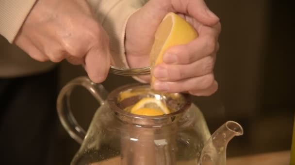 Close-up de mãos femininas estão cortando uma faca com limões em pedaços e espremendo para fazer chá em uma mesa de madeira de cozinha caseira. Casa chá de cozinha — Vídeo de Stock