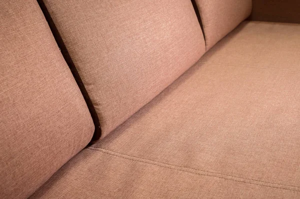 Крупный план фрагмента дорогого бежевого текстильного дивана в комнате — стоковое фото