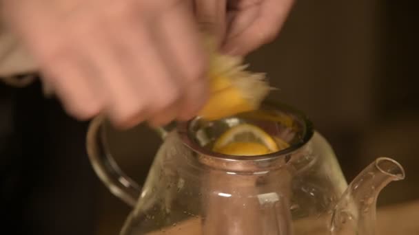 Close-up de mãos femininas estão cortando uma faca com limões em pedaços e espremendo para fazer chá em uma mesa de madeira de cozinha caseira. Casa chá de cozinha — Vídeo de Stock