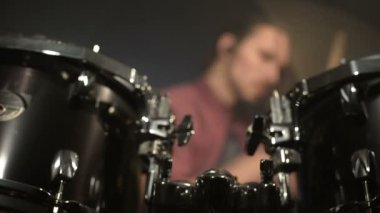 Uzun saçlı davulcular davul kiti karanlık bir odada bir siyah arka plan üzerinde oynamak. Rock müzisyeni. Statik plan. Geniş açı