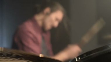 Uzun saçlı davulcular davul kiti karanlık bir odada bir siyah arka plan üzerinde oynamak. Rock müzisyeni. Statik plan. Geniş açı