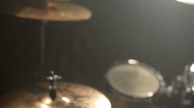 Uzun saçlı davulcular davul kiti karanlık bir odada bir siyah arka plan üzerinde oynamak. Rock müzisyeni. Statik plan. Geniş açı