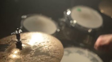 Uzun saçlı davulcular davul kiti karanlık bir odada bir siyah arka plan üzerinde oynamak. Rock müzisyeni. Statik plan. Geniş açı