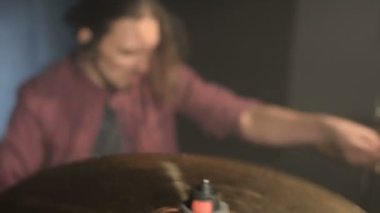 Uzun saçlı davulcular davul kiti karanlık bir odada bir siyah arka plan üzerinde oynamak. Rock müzisyeni. Statik plan. Geniş açı