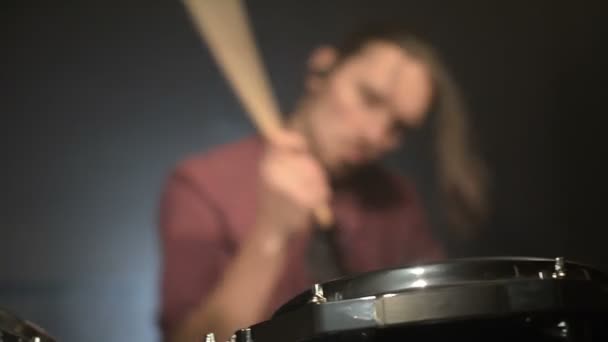 Bateristas de cabelos compridos tocam bateria em uma sala escura em um fundo preto. Músico de rock. Plano estático. Ângulo largo — Vídeo de Stock