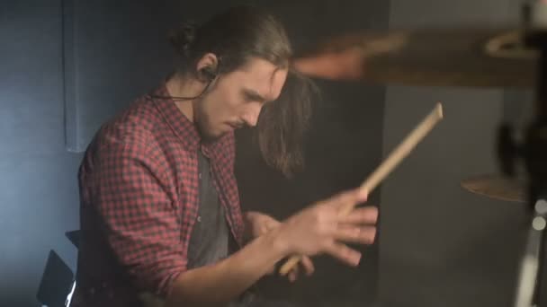 Un batteur aux cheveux longs assis à la batterie avec des bâtons de batterie à la main oscille au rythme de la musique sur l'intro de la chanson. le plaisir de jouer de la batterie. Plan statique. Grand angle — Video