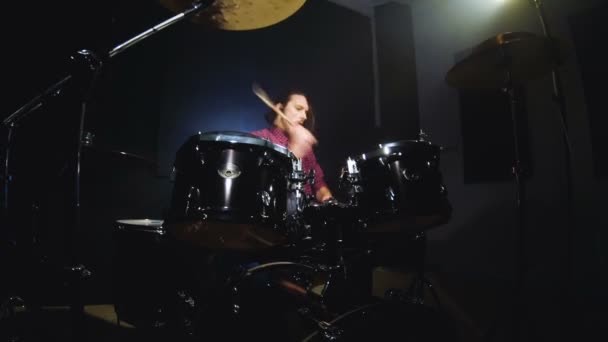 Bateristas de cabelos compridos tocam bateria em uma sala escura em um fundo preto. Músico de rock. Plano estático. Ângulo largo — Vídeo de Stock