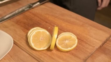 Kız ev mutfakta elinde closeup dilimlenmiş limon şarkıları bir tabak bir tepsi üzerinde düzenleme. Sağlıklı ev yemekleri