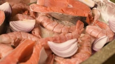 Yakın çekim deniz ürünleri protvine üzerinde. Çiğ somon kızartma için karides ve çiğ soğan ile. Sığ derinlik-in tarla. üstten görünüm