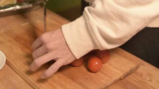 Крупный план рук девушки на домашней кухне на деревянной разделочной доске с помидорами черри. Домашняя кухня — стоковое видео